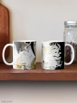 coppia di tazze classiche con design astratto dai colori fluidi con contrasti di bianco e nero e sfumature di giallo su mensola